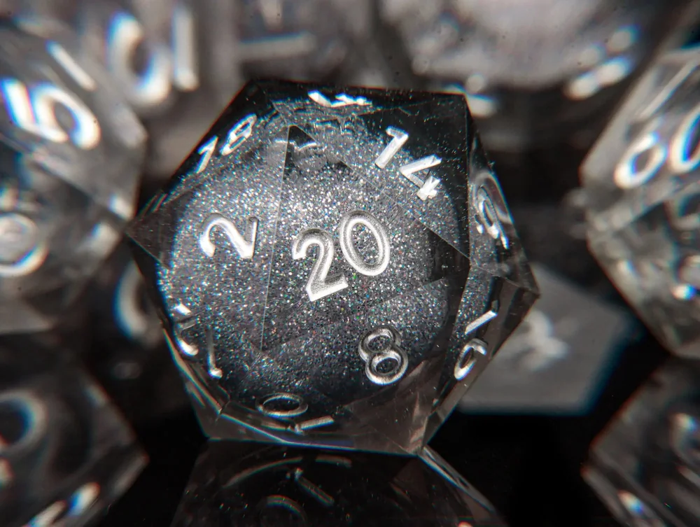 Close-up of a clear liquid-core D20 showing its glitter centre and the 20 face