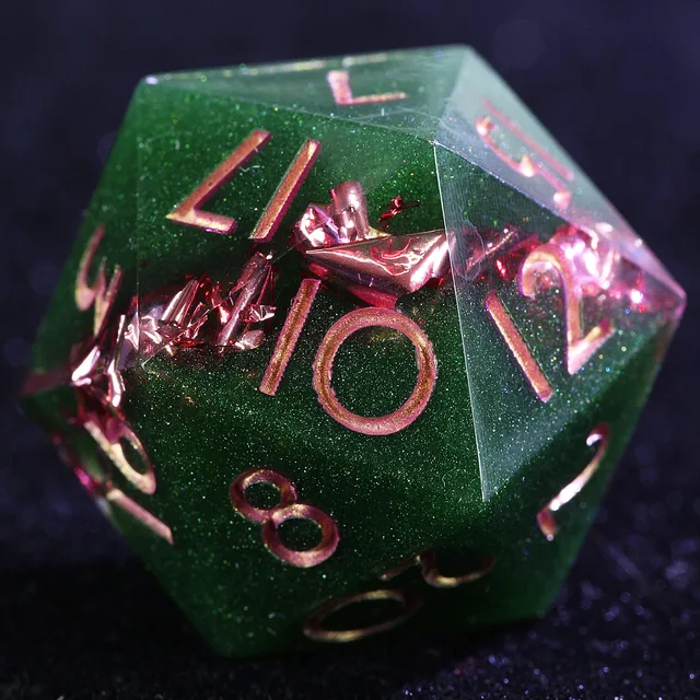 Close-up of a green glittery twenty-sided die with pink numerals and pink foil-like inclusions.