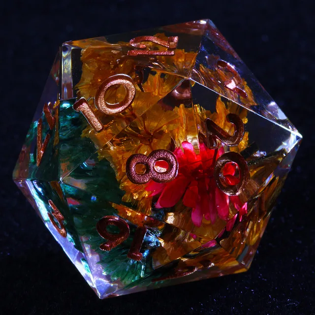 Close-up of a clear D20 with red, yellow and teal flower-like inclusions and copper-coloured numbers.