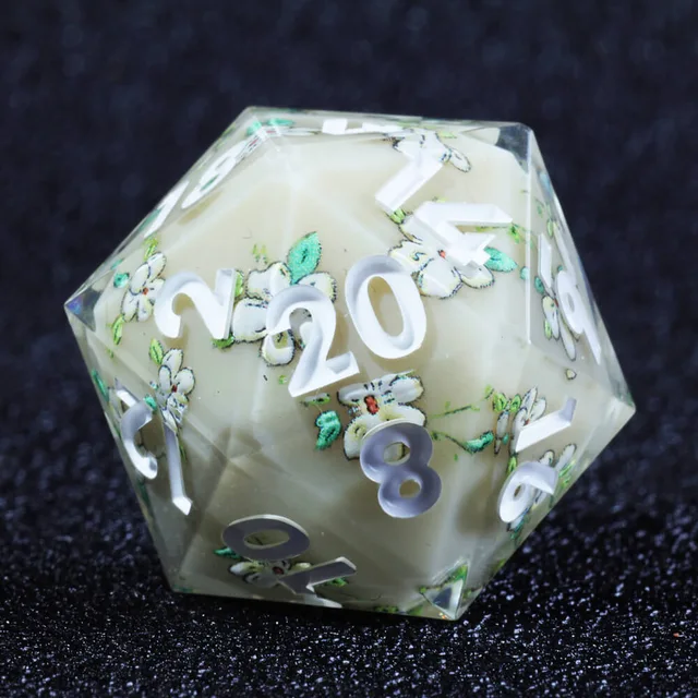 Close-up of a floral ivory-centred D20 with white numerals on dark fabric.