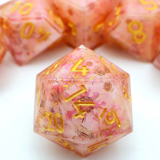 Close-up of a peach-pink floral D20 with gold numbers.