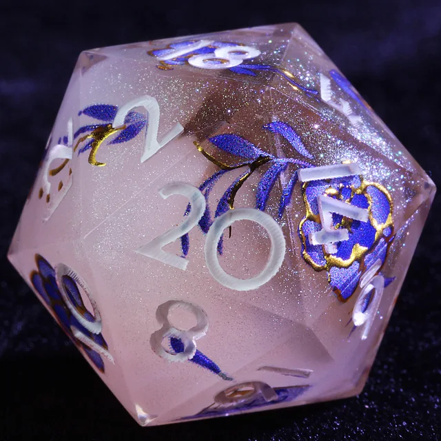 Close-up of a pale pink glittering D20 with white numerals and blue flowers outlined in gold.