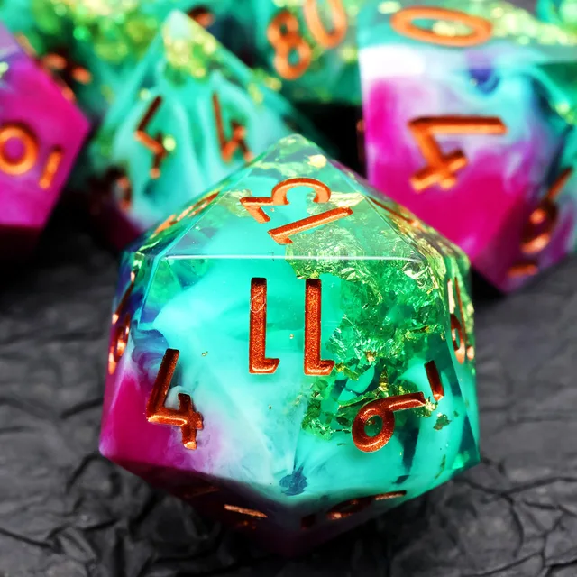 Close-up of a turquoise polyhedral die with gold-coloured flakes and copper-orange numbers.