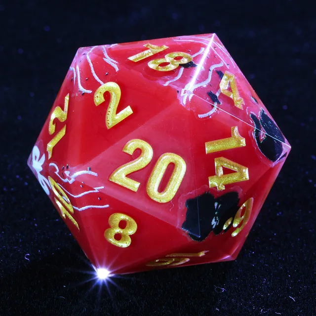 Red D20 with gold numbers and black cat motifs on dark fabric.