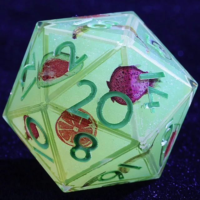 Close-up of a pale green D20 with green numbers and colourful fruit designs.