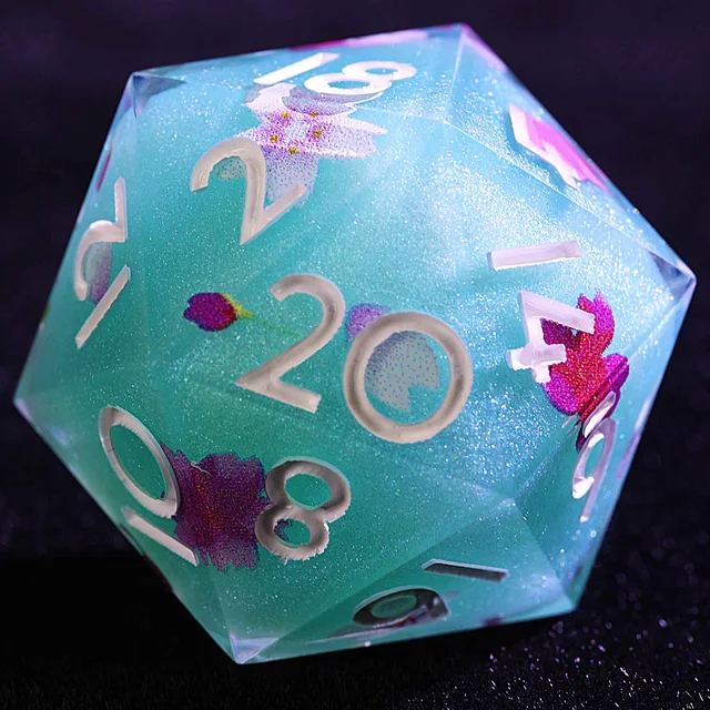Close-up of a turquoise shimmering D20 with pale numbers and pink clover and flower patterns.