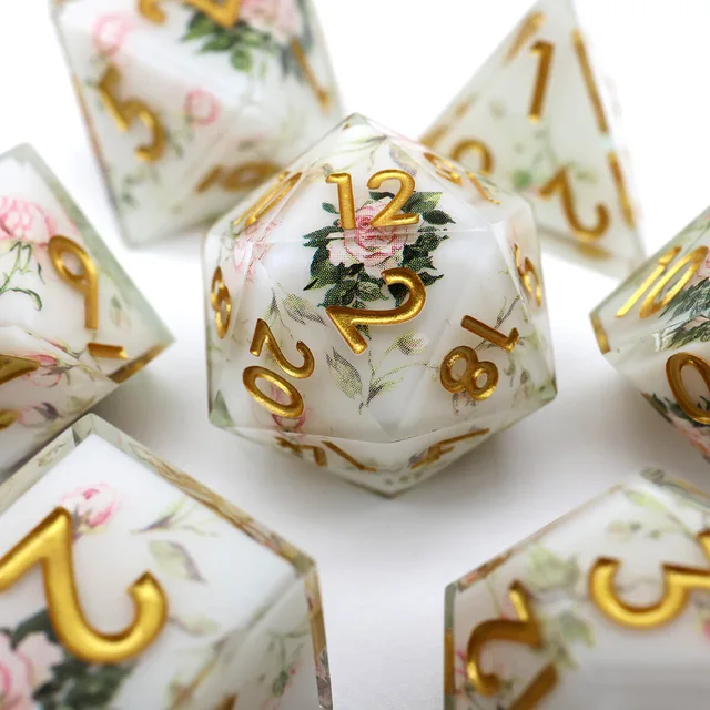 Close-up of a white floral D20 with gold numbers and other matching dice behind it.