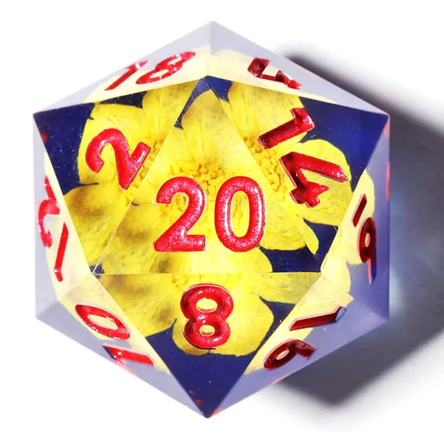 Close-up of a blue and clear D20 with yellow floral inclusions and red numbers.