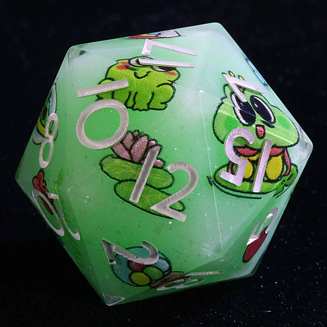 Close-up of a mint-green numbered die with cartoon frogs and lily pads.