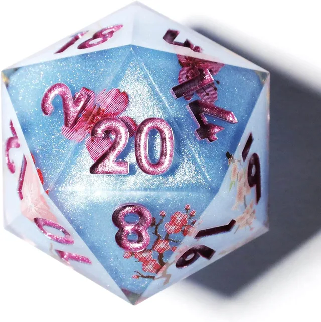 Close-up of a blue glitter D20 with pink numbers and blossoms.