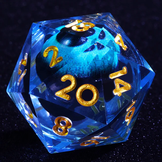 Close-up of a transparent blue D20 with gold numbers and a turquoise-blue eye-like core.