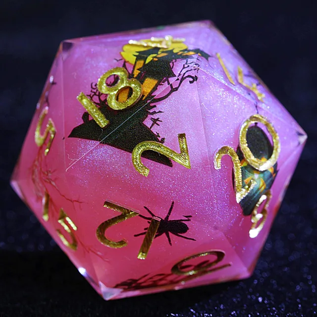 Close-up of a pink glitter D20 with gold numbers and a haunted-house illustration.
