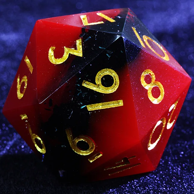 Close-up of a crimson and black polyhedral die with gold numbers.