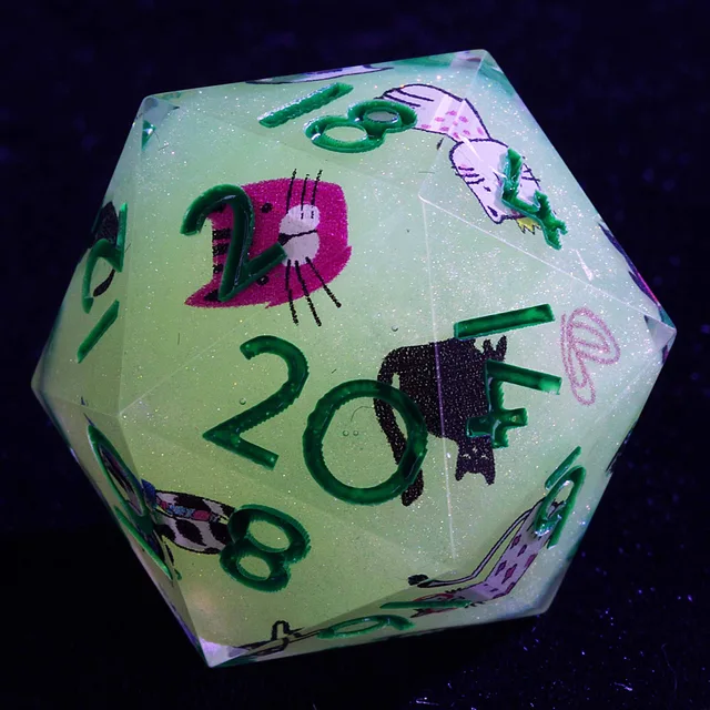 Close-up of a pale green glittery D20 with green numbers and cat illustrations.