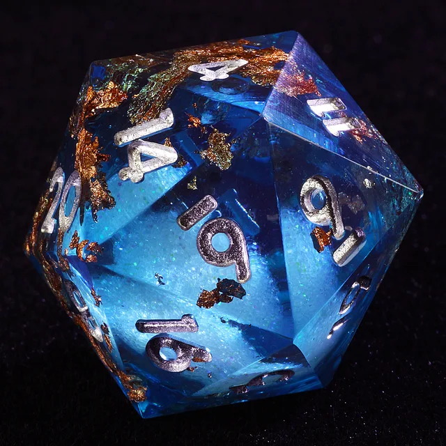 Close-up of a transparent blue D20 with silver numerals and copper-gold flakes.