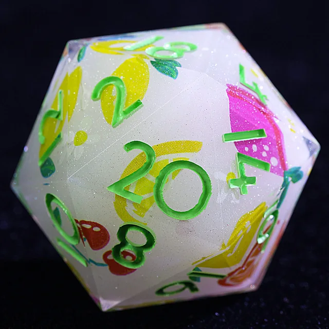 Close-up of a pale translucent D20 with green numbers and colourful fruit illustrations.