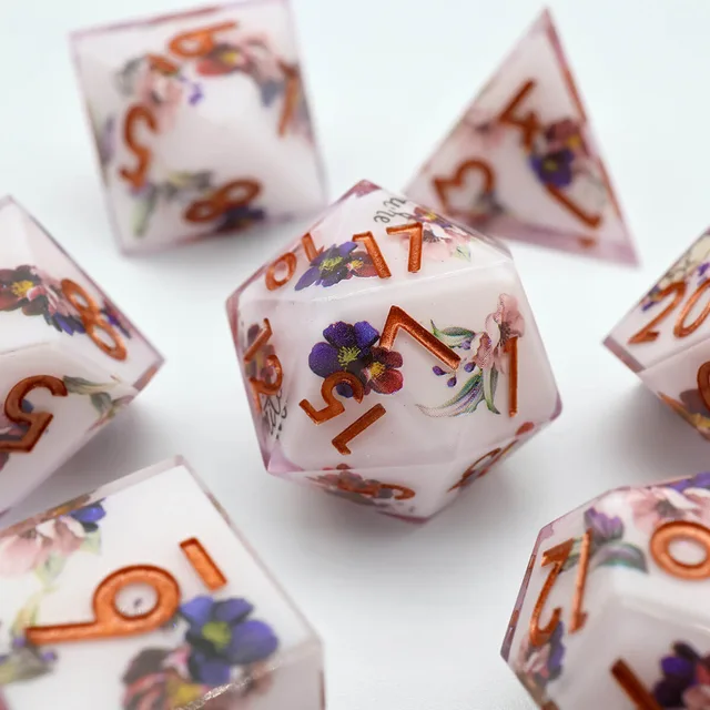 Close-up of a floral D20 with copper-coloured numbers and pale pink edges