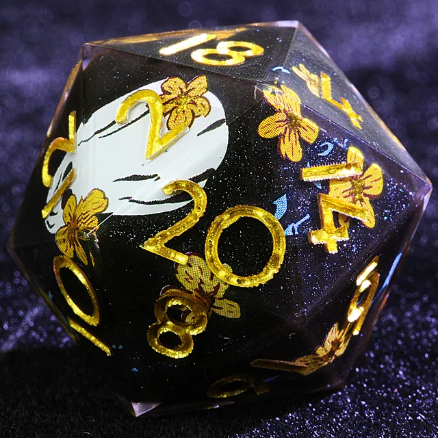 Close-up of a dark glitter-flecked D20 with gold numbers, gold flowers and a white illustration.