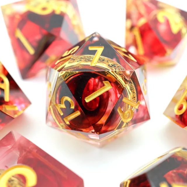 Close-up of a sharp-edged red D20 with gold numbers and a gold ring inclusion.