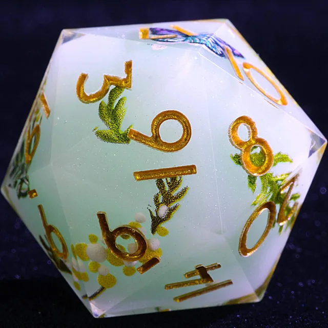 Close-up of a pale blue-green polyhedral die with gold numbers and floral foliage.
