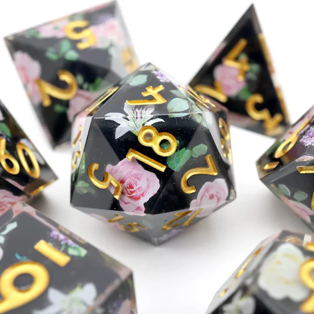 Close-up of a black floral D20 with gold numbers.
