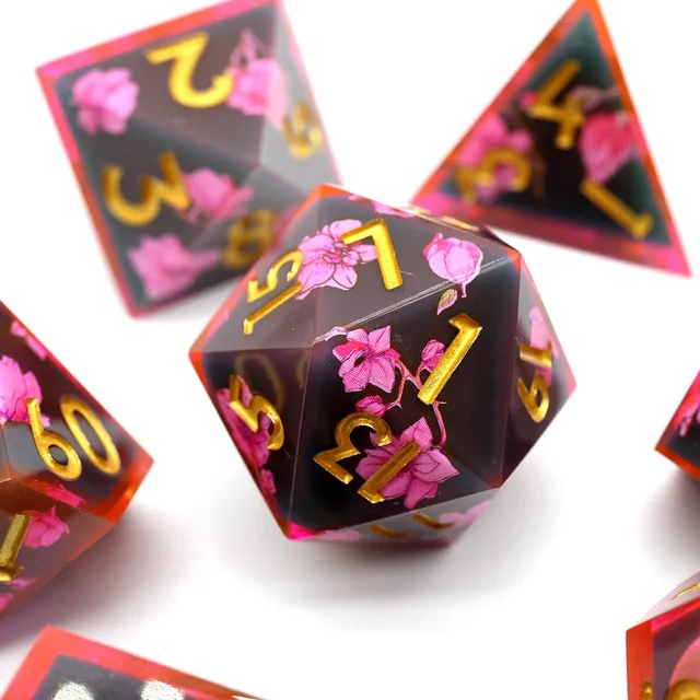 Close-up of a dark floral D20 with gold numbers.