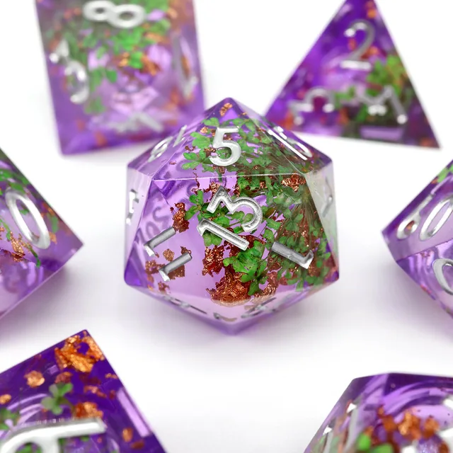 Close-up of a purple D20 with green floral inclusions and silver numerals.