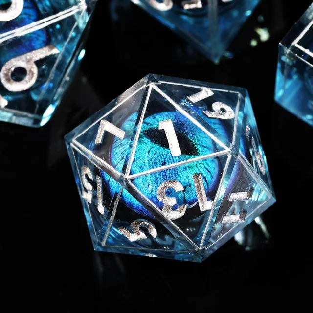 Close-up of a transparent blue D20 with a turquoise slit-pupil eye and silver numbers.