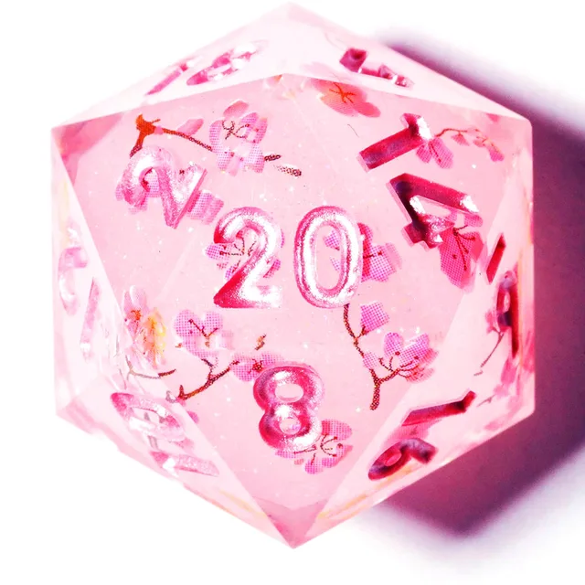 Close-up of a translucent pink D20 with blossoms and glittery pink numbers.