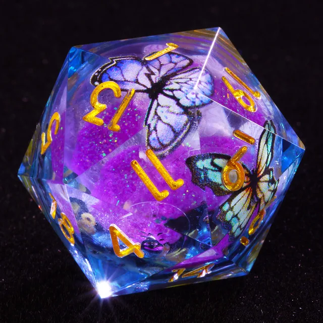 Close-up of a transparent blue-edged D20 with gold numbers, purple glittering core and butterflies.