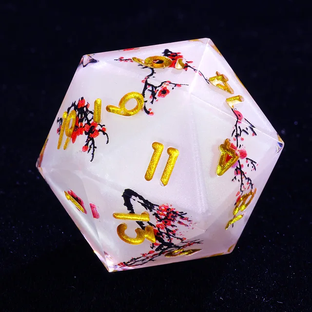 Close-up of a white D20 with clear edges, red blossoms, black branches, and gold numbers.