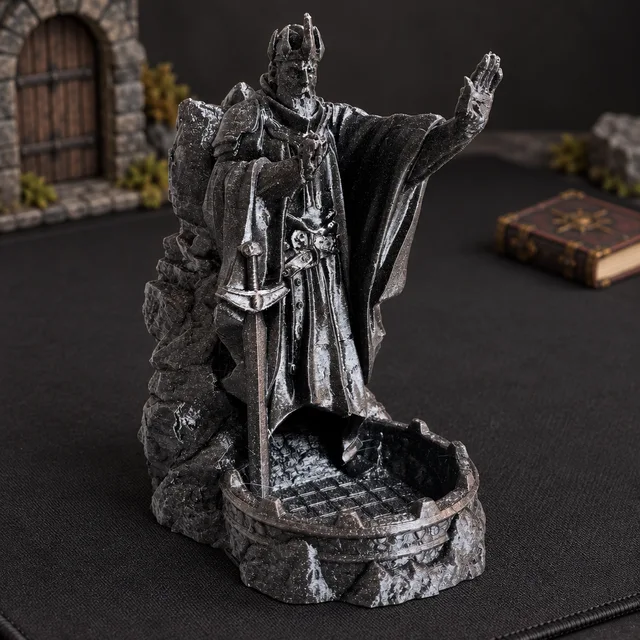 Black tabletop gaming tower with silvery highlights, a crowned robed figure raising one hand above a rounded dice tray.