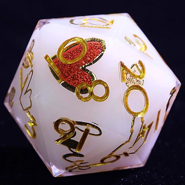 Close-up of a pale white polyhedral die with gold numbers and a glittering red heart.