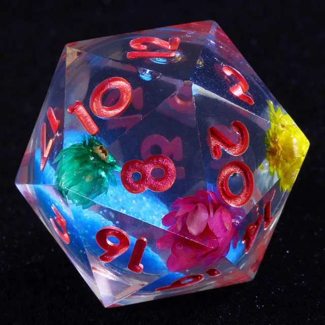 Clear D20 with red numbers, blue glittery core and colourful flowers on black.