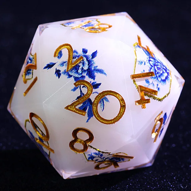 Close-up of a white D20 with blue flowers and gold-coloured numbers.