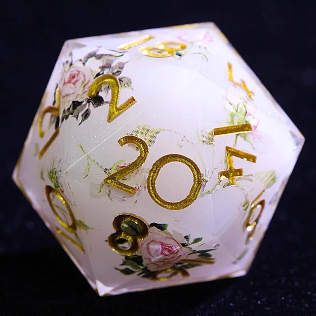 Close-up of a milky-white D20 with pink roses, green leaves, and gold numbers.