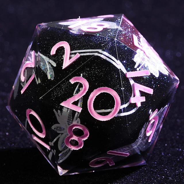 Close-up of a clear D20 with a dark glittery centre, pale floral pattern and pink numerals.
