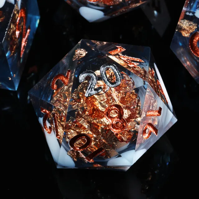 Close-up of a blue D20 with copper-coloured flakes and metallic numbers.