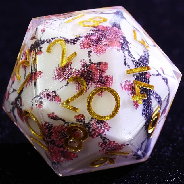 Close-up of a pale D20 with pink flowering branches, clear edges and gold numbers.