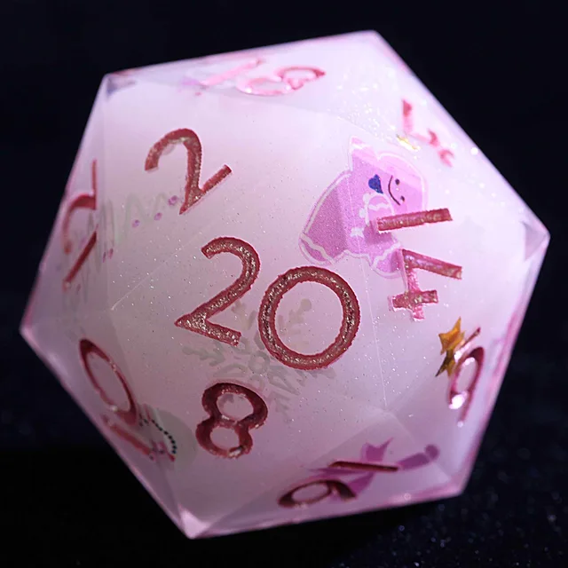 Close-up of a pale pink D20 with glittery rose-pink numbers and a pink cartoon figure.