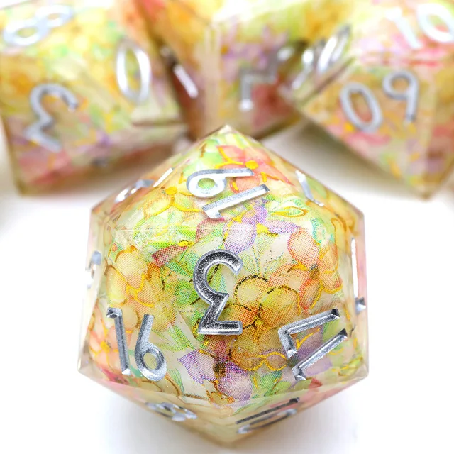 Close-up of a translucent floral D20 with pastel flowers and silver-coloured numbers.