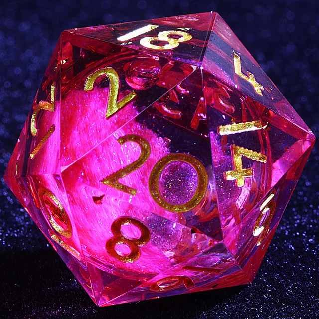 Close-up of a transparent crimson-pink D20 with a glittering inner core and gold numbers.