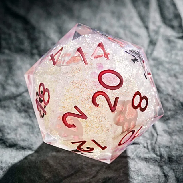 Close-up of a glittering pale pink D20 with paw prints and rose-coloured numerals.