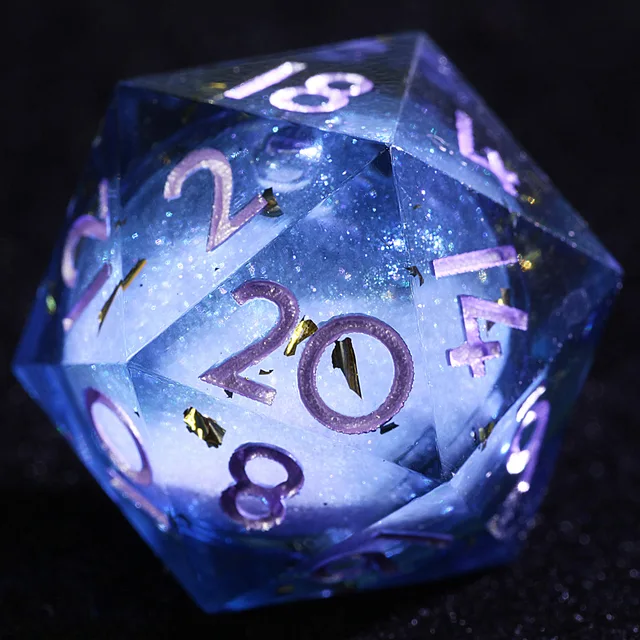 Close-up of a transparent blue D20 with a pale inner core, gold flecks and purple numbers.
