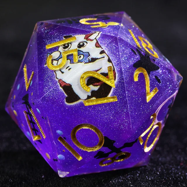 Close-up of a glittery purple D20 with gold numbers and a white cat illustration.