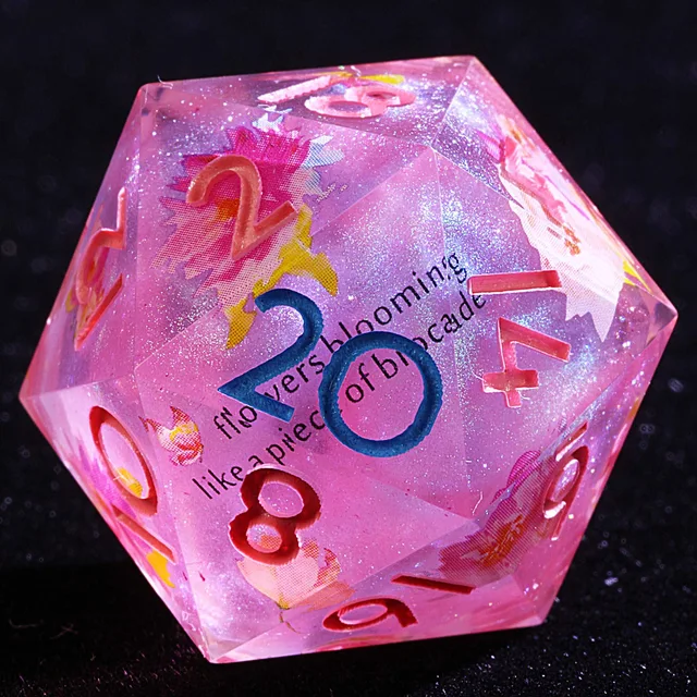 Close-up of a glittery pink-purple floral D20 with a blue 20, coral numerals, and embedded script.