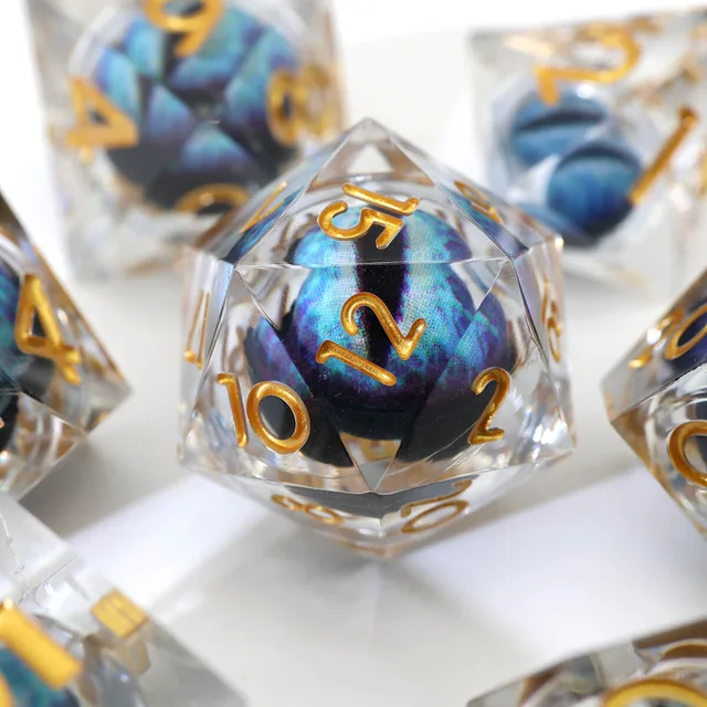 Close-up of a clear D20 with gold numbers and a blue-purple eye-like core.