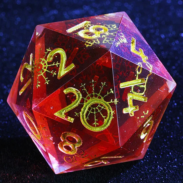 Close-up of a translucent red D20 with gold numbers and snowflake patterns.