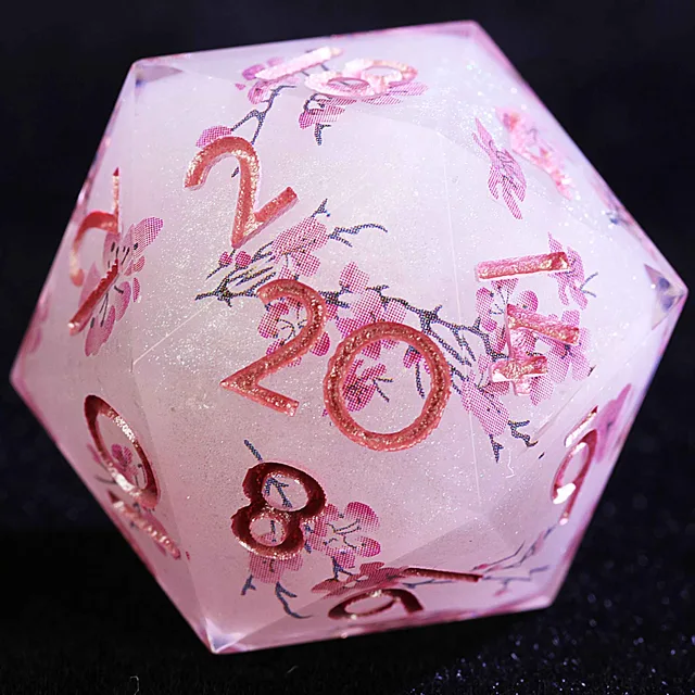 Close-up of a pale pink glittering D20 with blossom branches and rose-pink numbers.