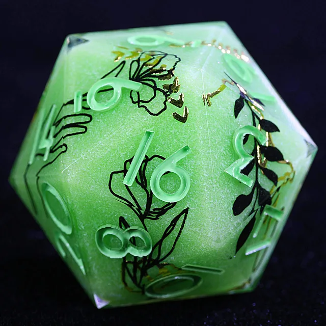Close-up of a pale green D20 with mint numerals, black flowers and gold accents.